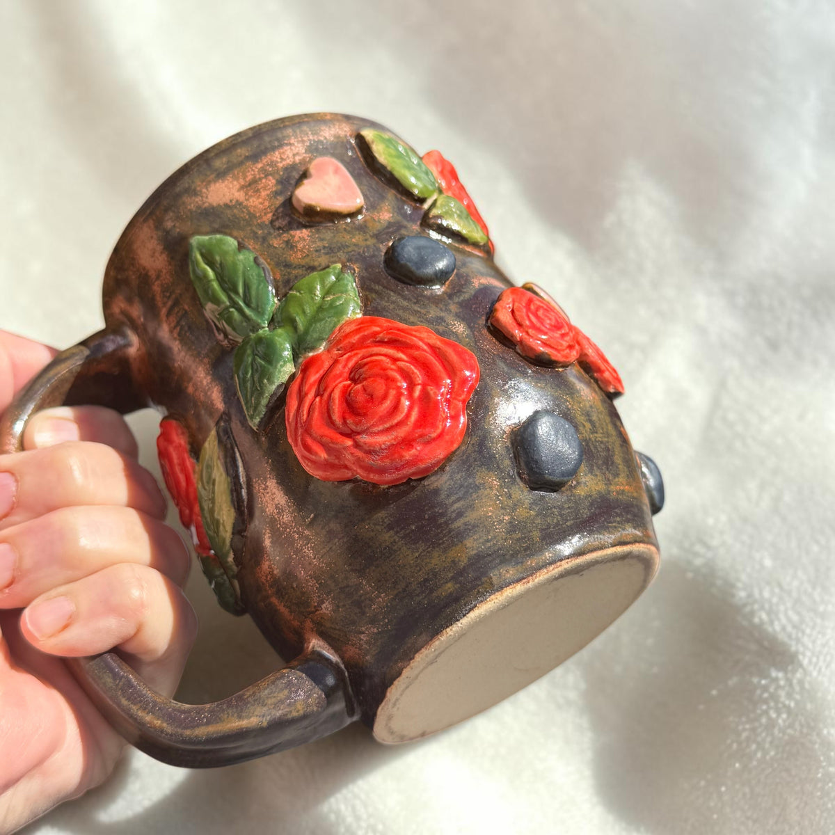 Rock N Art Shop handmade stoneware mug with bronze glaze, dimensional red roses, green leaves, and pink hearts