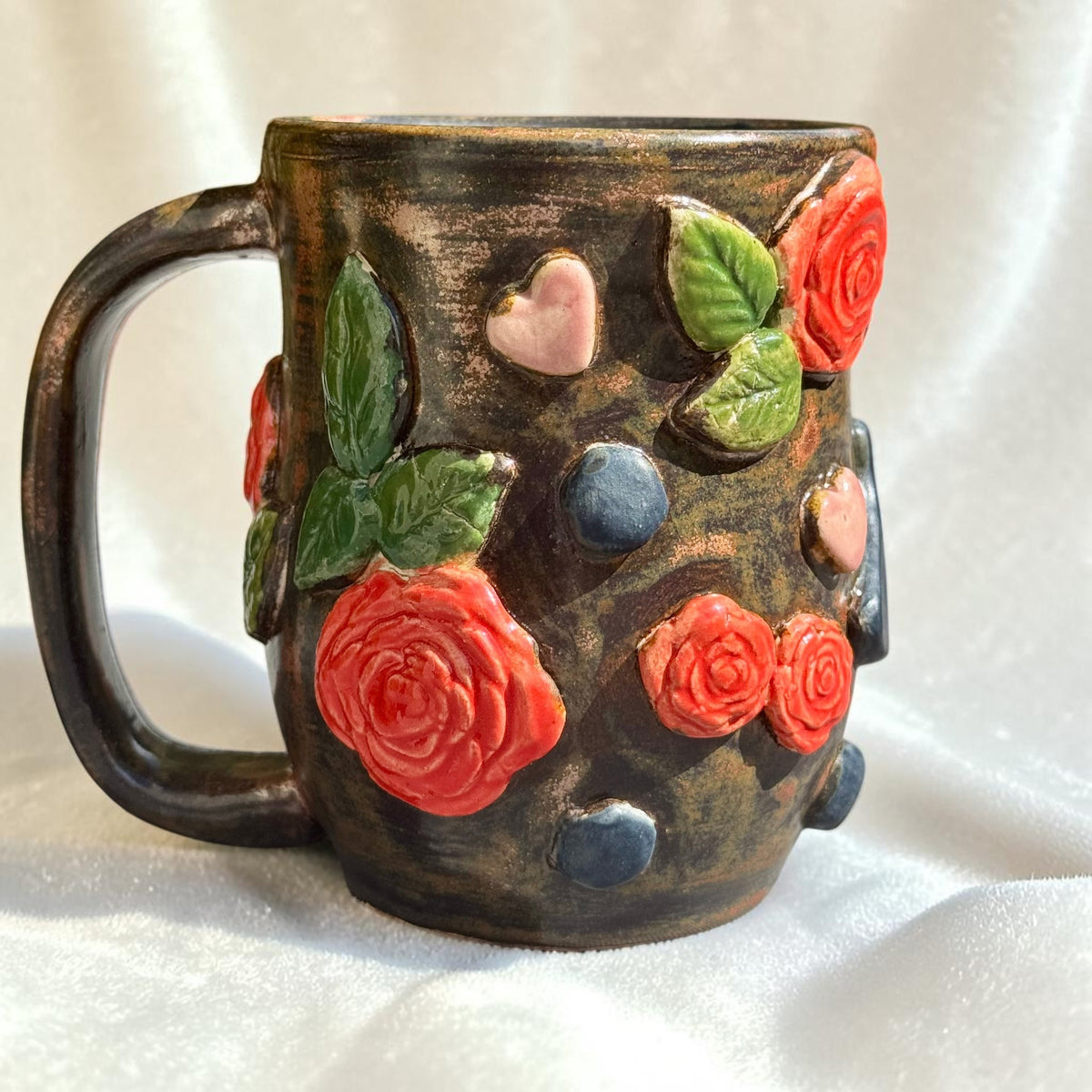 Rock N Art Shop handmade stoneware mug with bronze glaze, dimensional red roses, green leaves, and pink hearts.