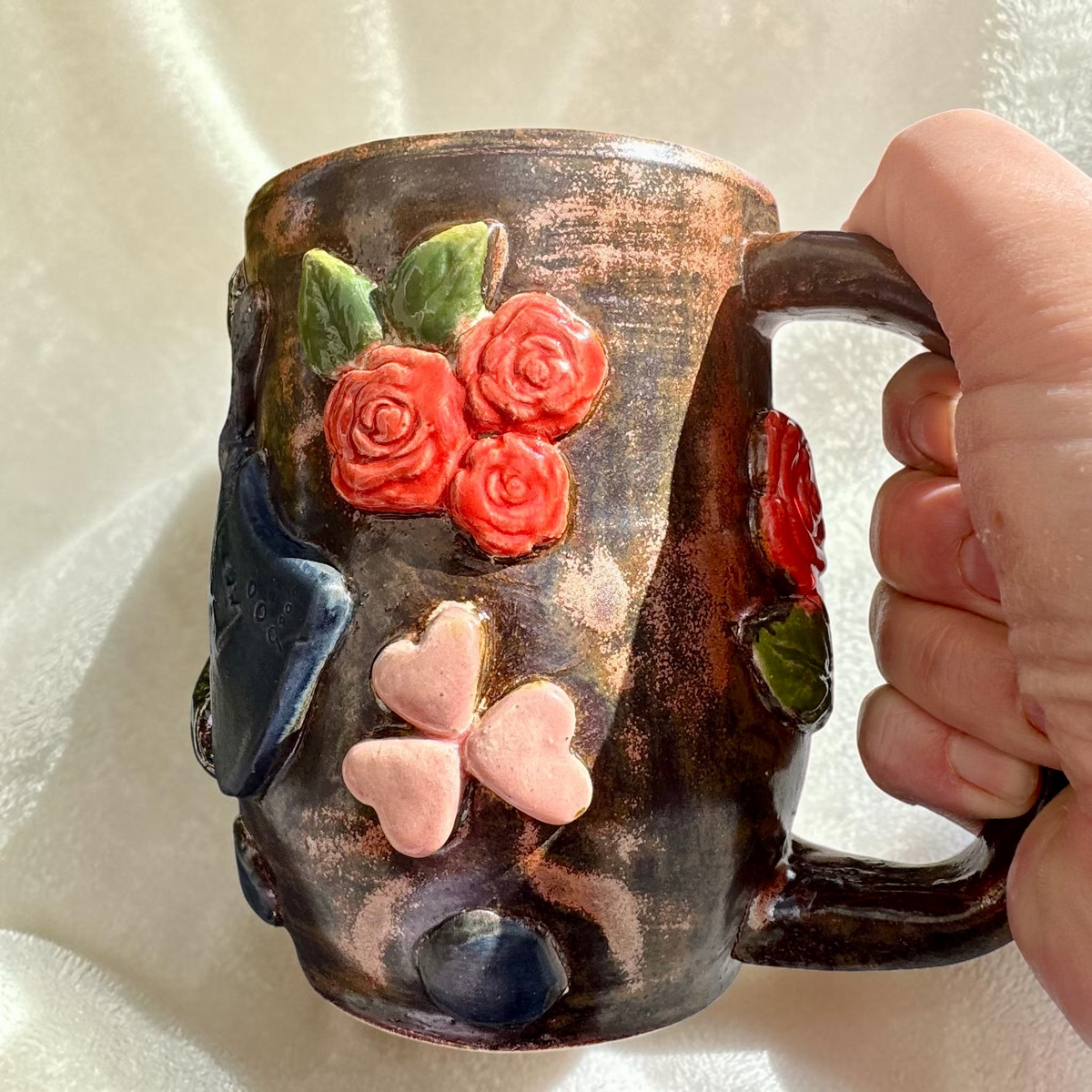 Rock N Art Shop handmade stoneware mug with dimensional red roses, pink hearts, and bronze-toned metallic glaze.