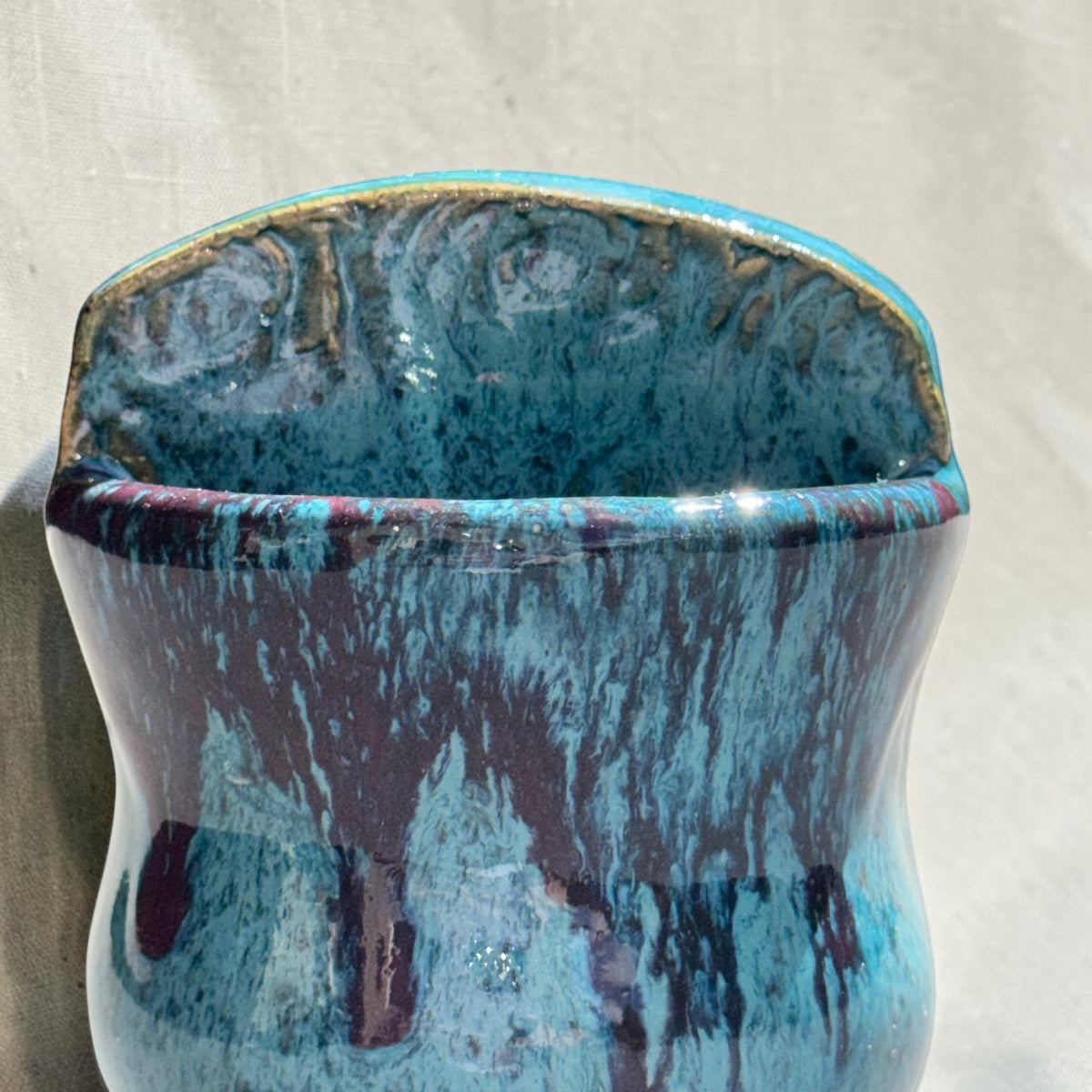 Rock N Art Shop turquoise and blue stoneware wall pocket vase with textured backplate and plum-brown glaze drips.