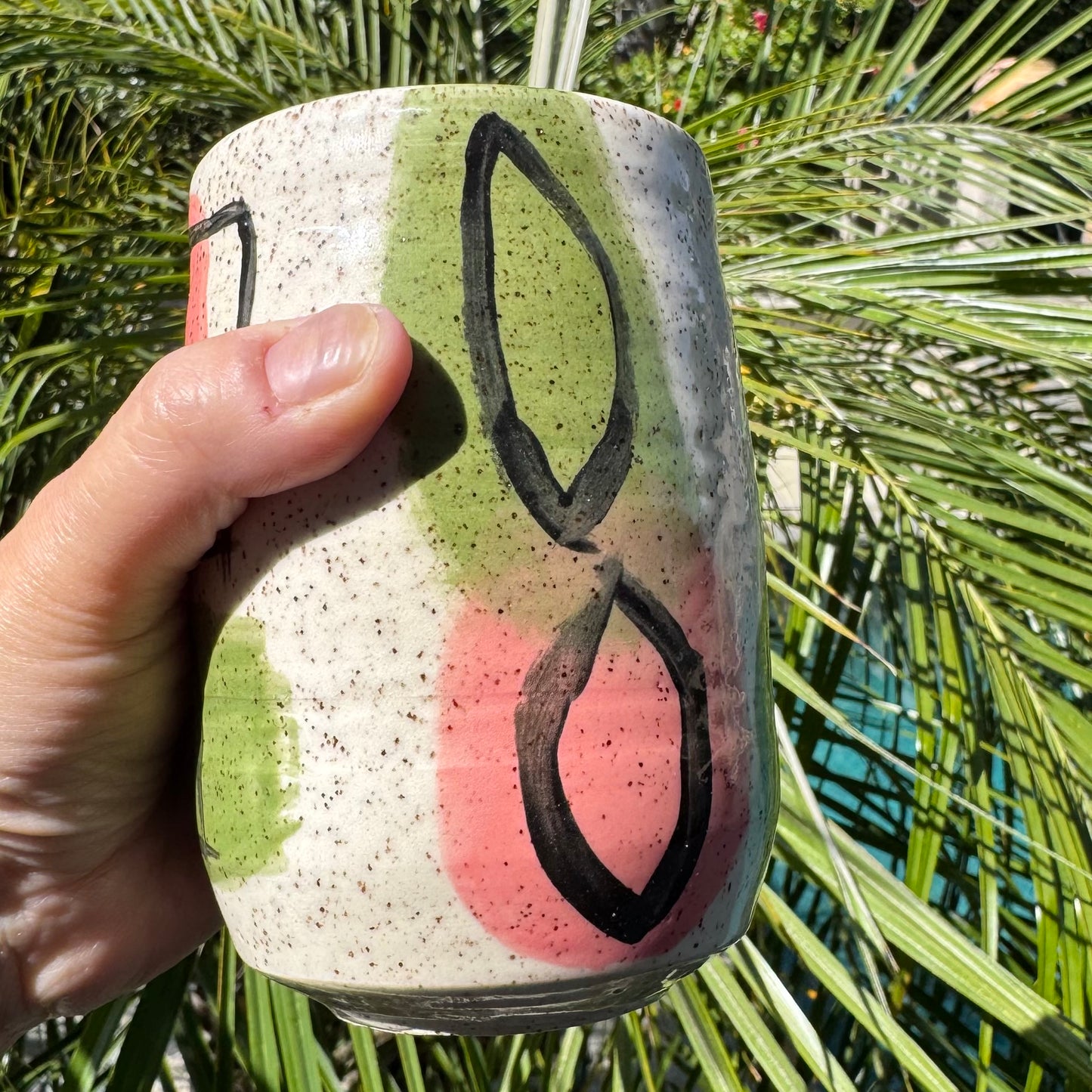 Stoneware tumbler with hand-painted abstract pink and green shapes and black line work, handmade pottery by Rock N Art Shop, Los Angeles