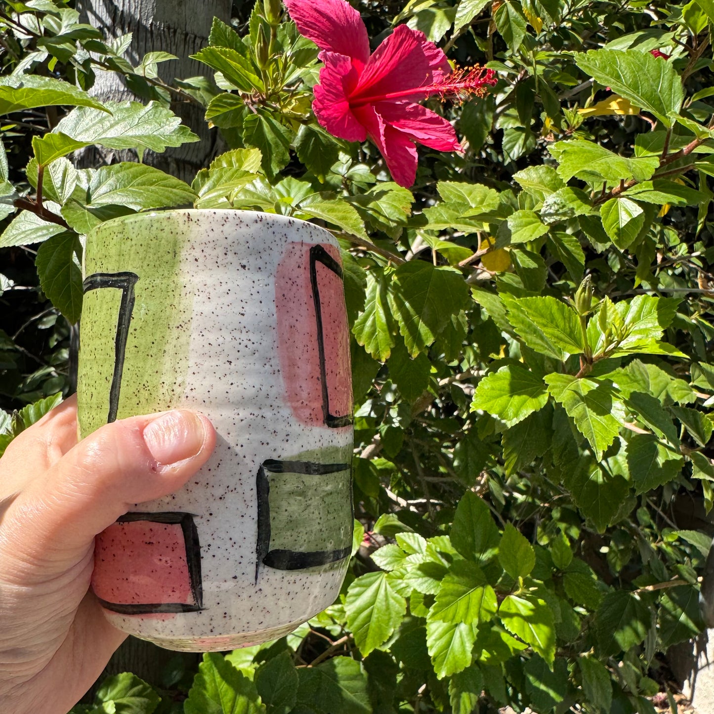 Stoneware tumbler with hand-painted abstract pink and green shapes and black line work, handmade pottery by Rock N Art Shop, Los Angeles