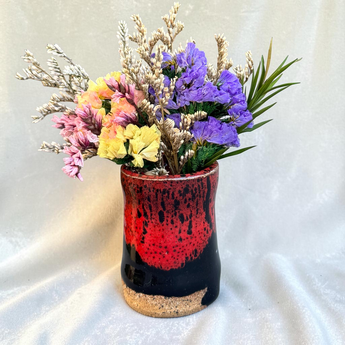 Rock N Art Shop mini ceramic bud vase with red and black glaze and exposed clay base, filled with colorful dried flowers