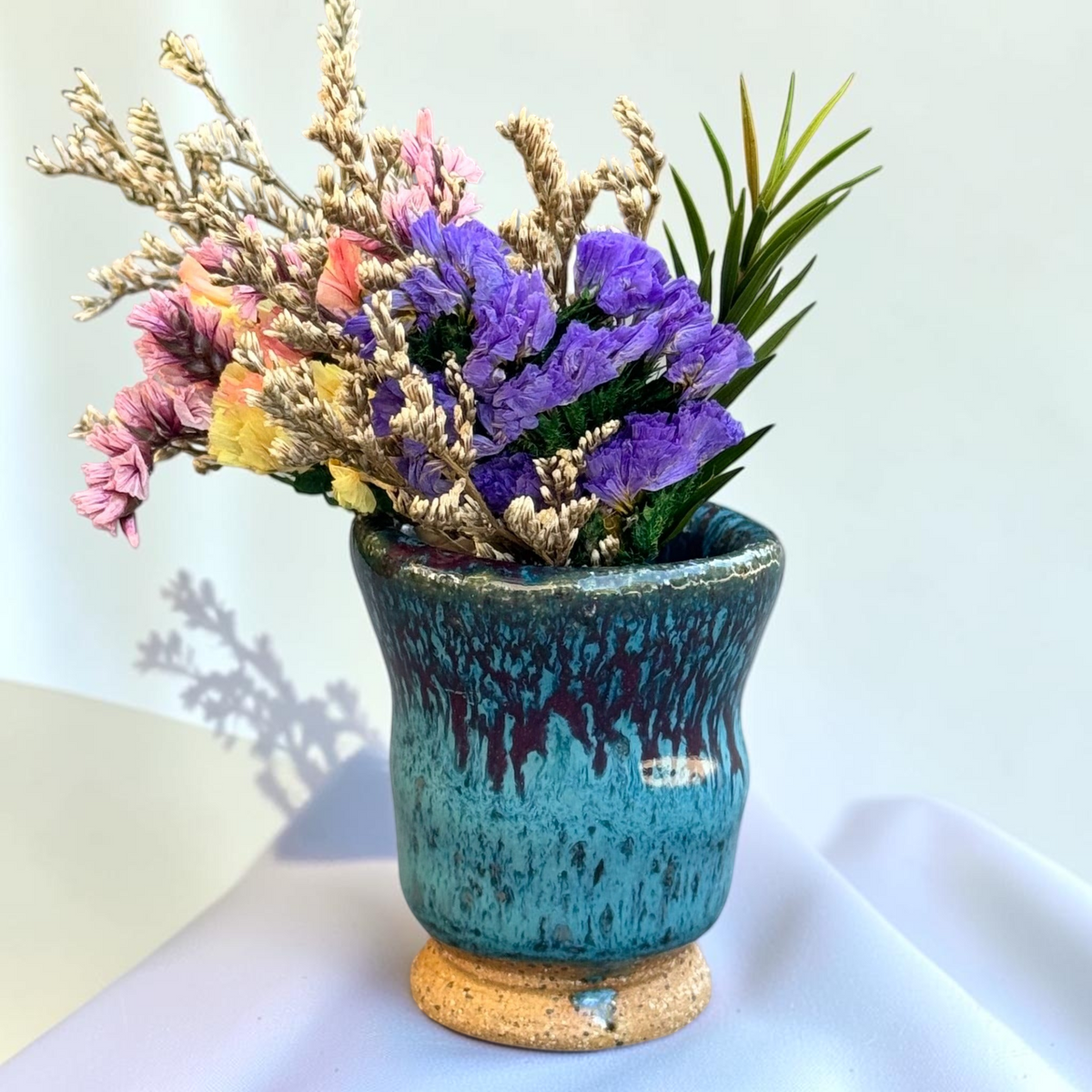 Rock N Art Shop miniature ceramic bud vase with turquoise and plum glaze, flared rim, and exposed speckled clay foot.