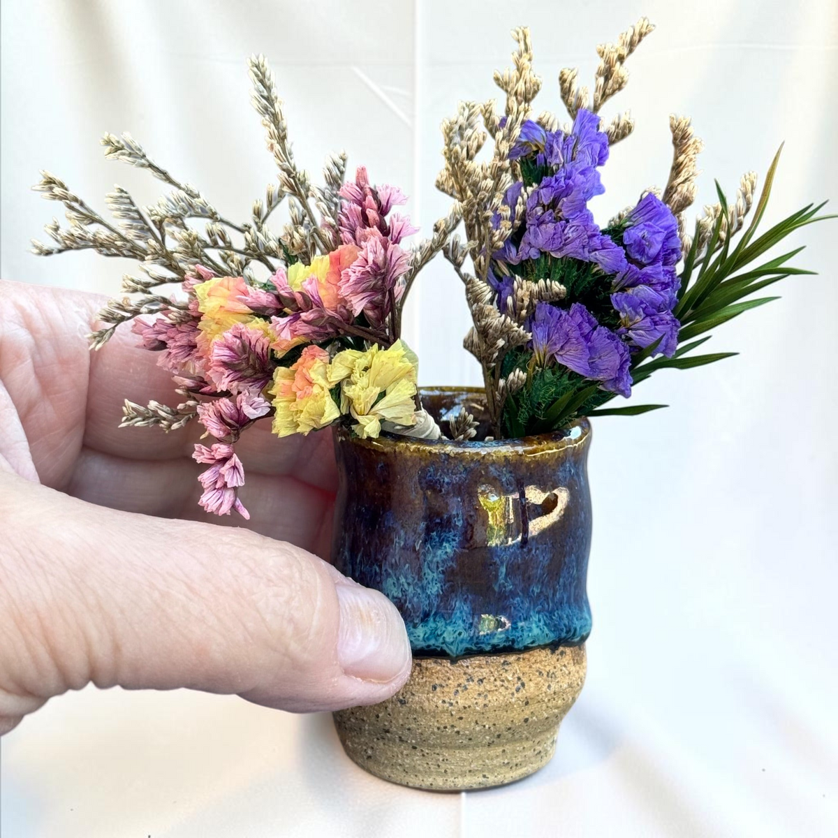 Rock N Art Shop miniature ceramic bud vase with blue, brown, and turquoise glaze and exposed speckled clay base.