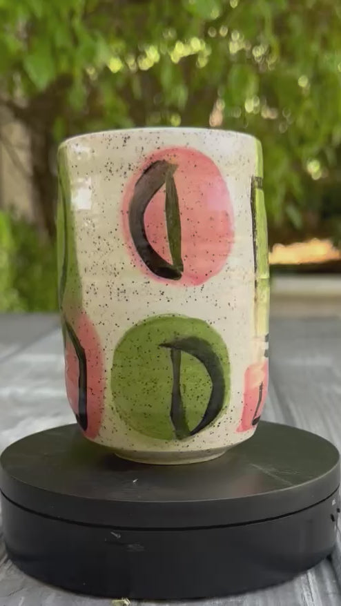 Stoneware tumbler with hand-painted abstract pink and green shapes and black line work, handmade pottery by Rock N Art Shop, Los Angeles