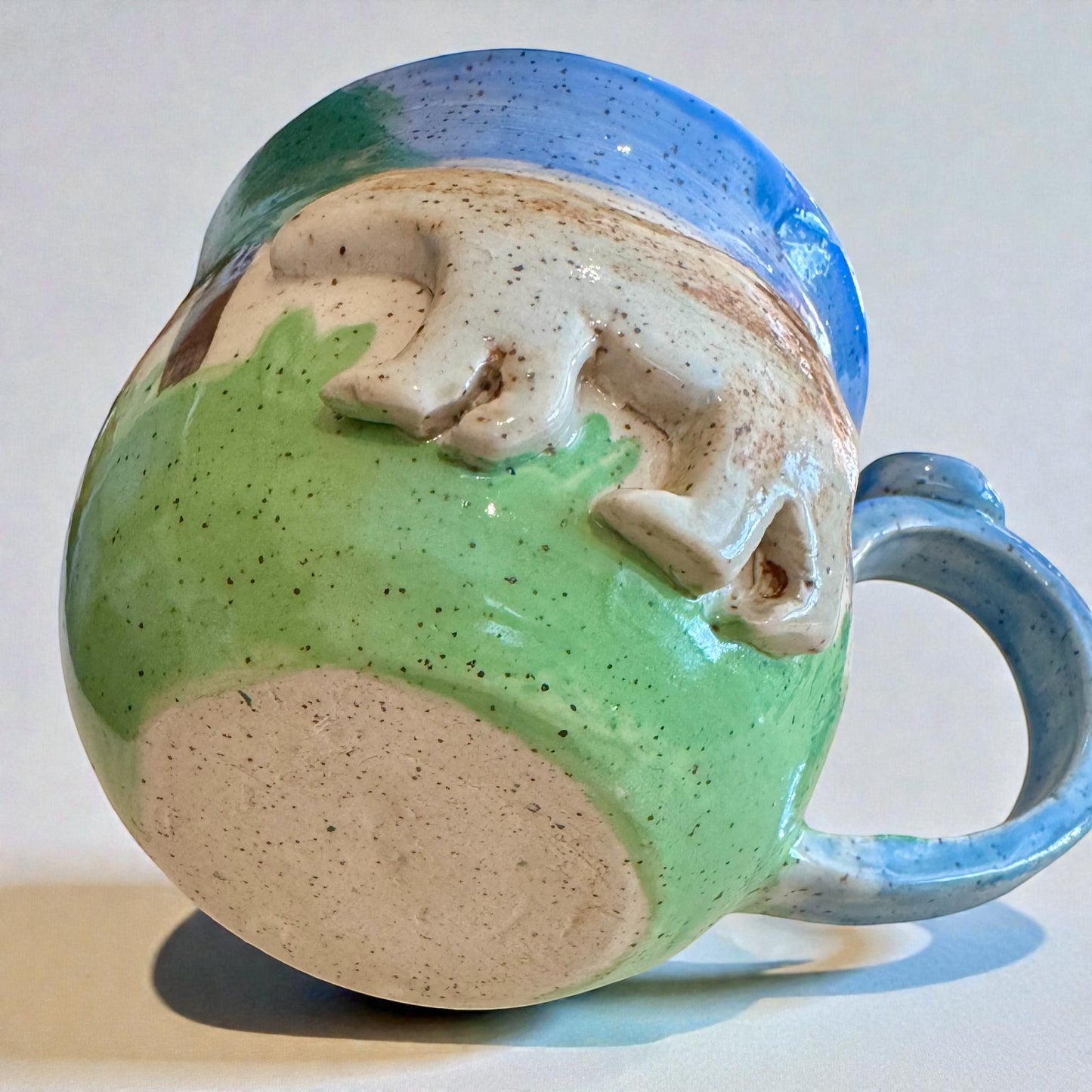 Rock N Art Shop Forest Bear Stoneware Mug with raised silhouette and forest scene, hand-glazed in cabin tones of blue, green, and brown.
