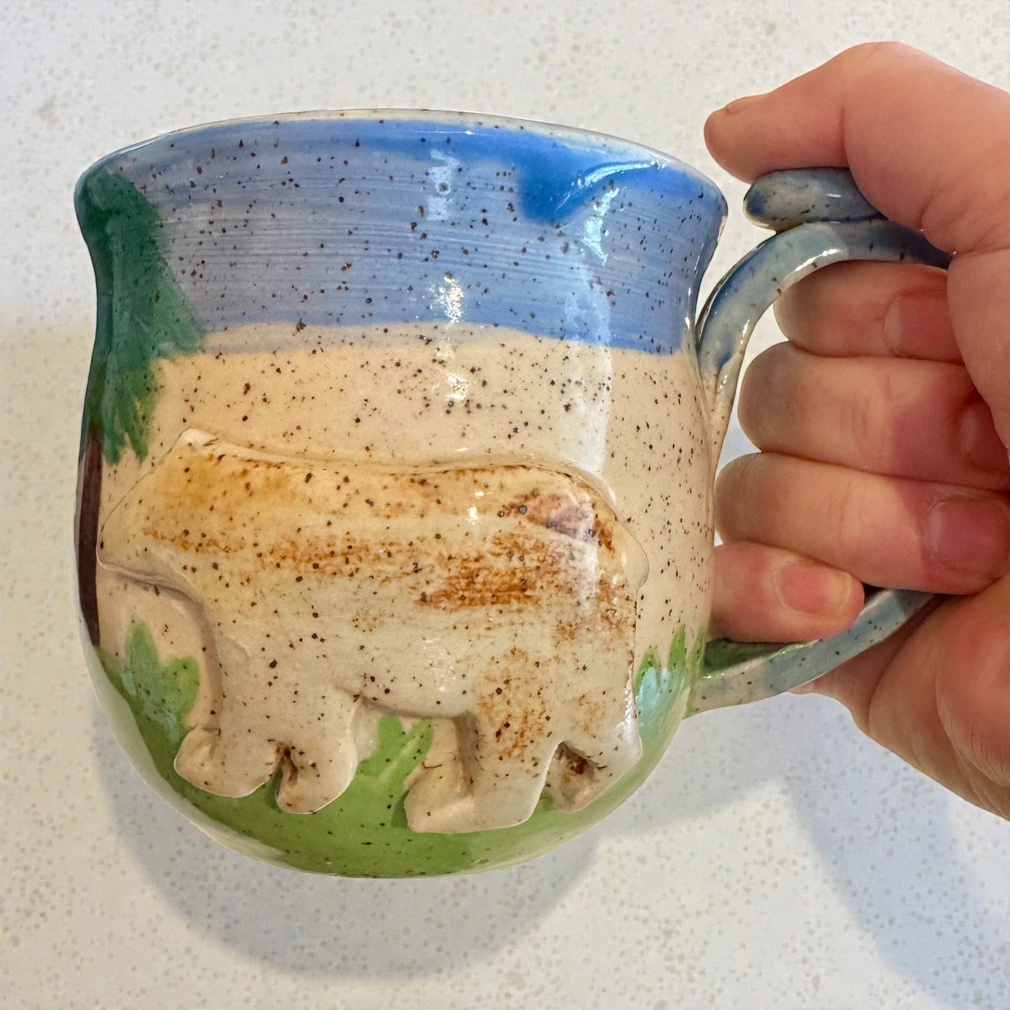 Rock N Art Shop Forest Bear stoneware mug with raised silhouette, hand-glazed in cabin tones of blue, green, and brown. 12 oz capacity.