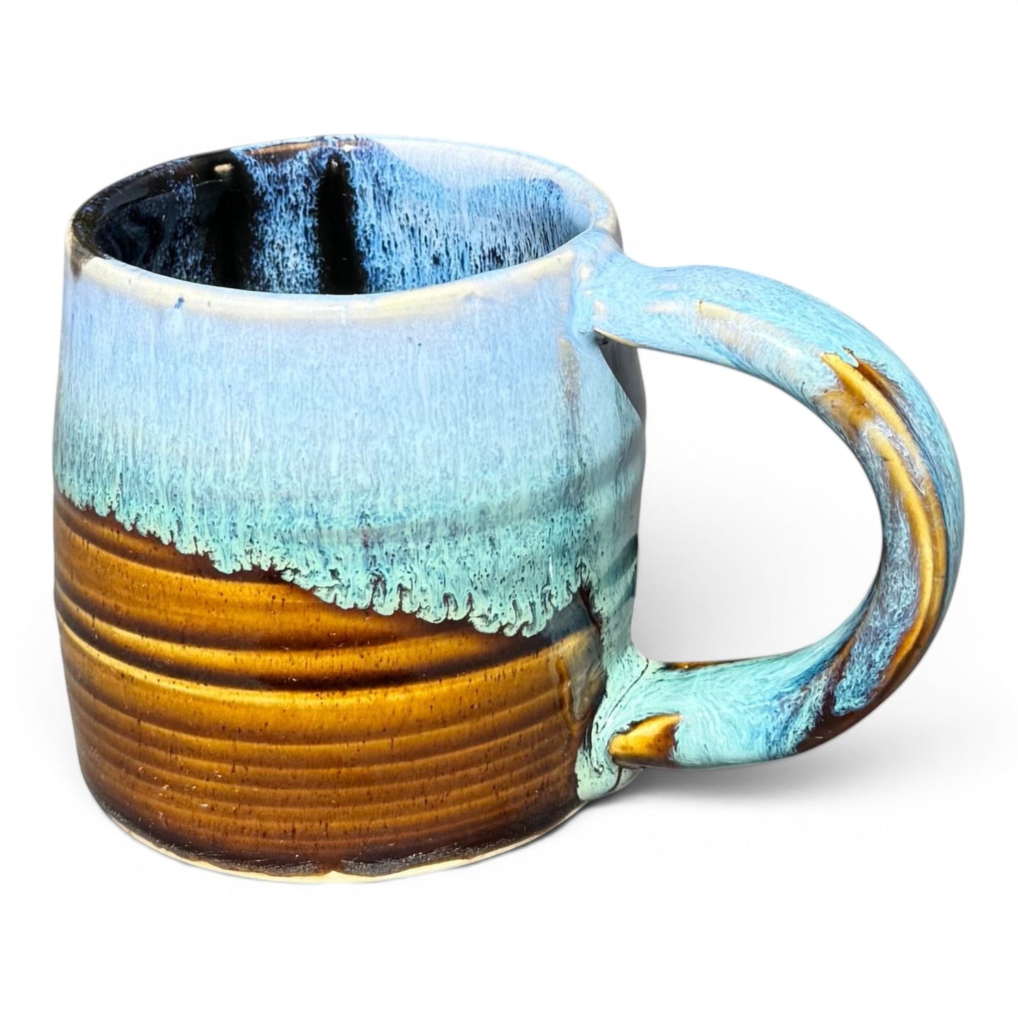 Rock N Art Shop 9 oz handmade stoneware mug with Castile Blue glaze pooling at the rim and Turkish Amber below. Glossy black interior.