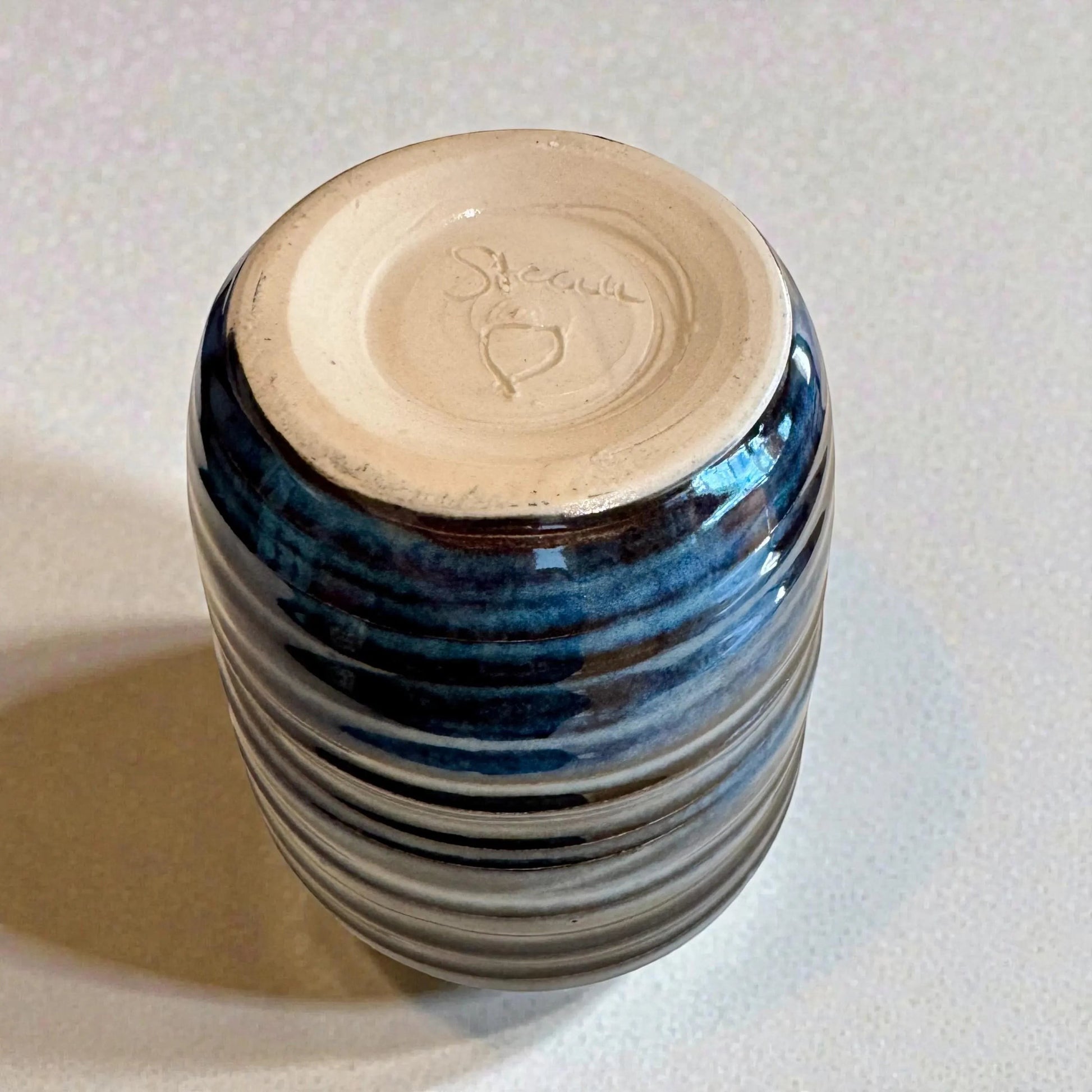 Rock N Art Shop handmade blue stoneware tumbler, 12 oz wheel-thrown pottery with layered blue glaze and horizontal texture.