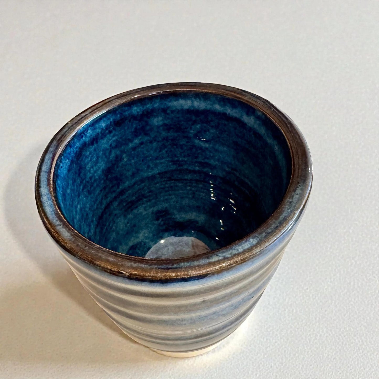 Rock N Art Shop handmade blue stoneware tumbler, 12 oz wheel-thrown pottery with layered blue glaze and horizontal texture.