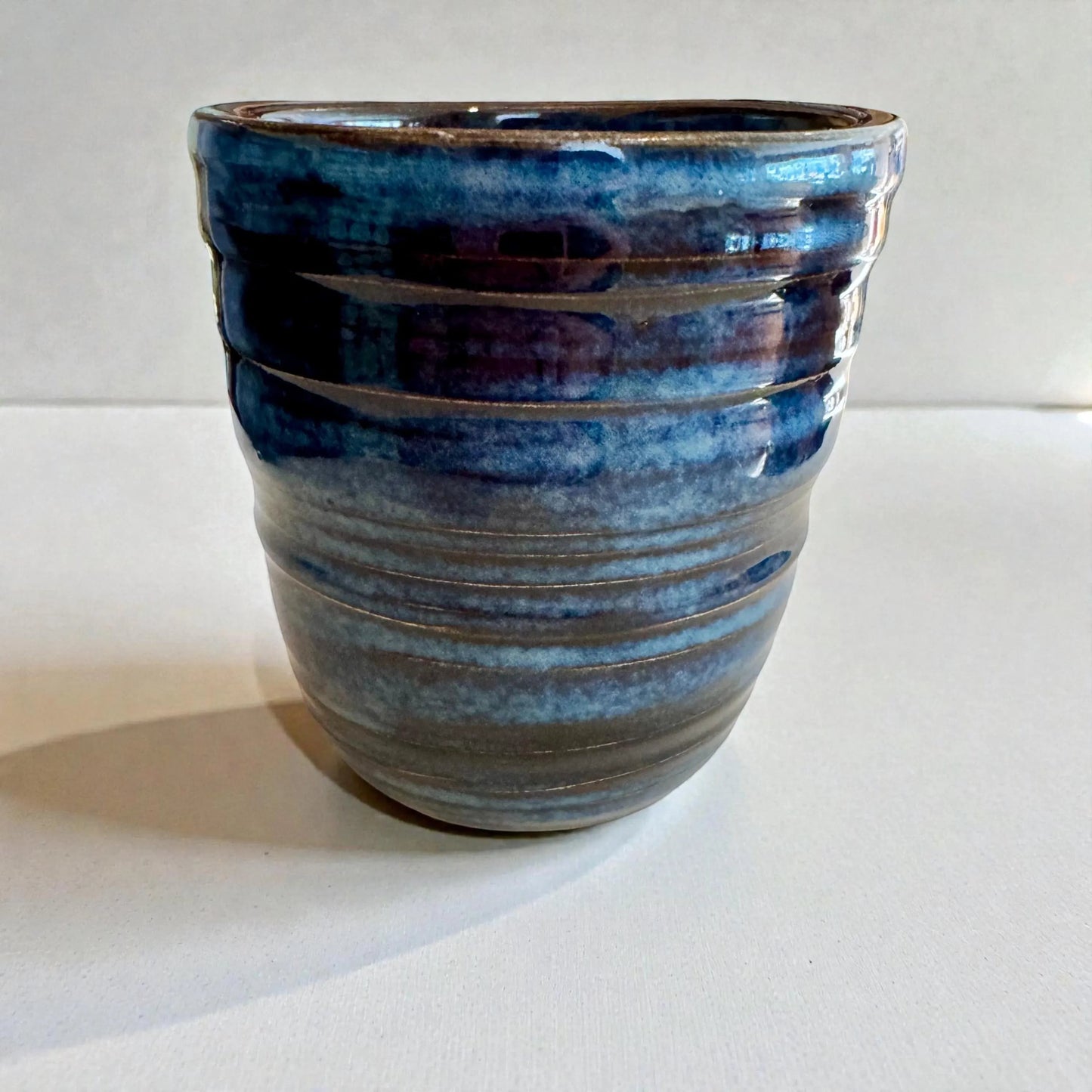 Rock N Art Shop handmade blue stoneware tumbler, 12 oz wheel-thrown pottery with layered blue glaze and horizontal texture.