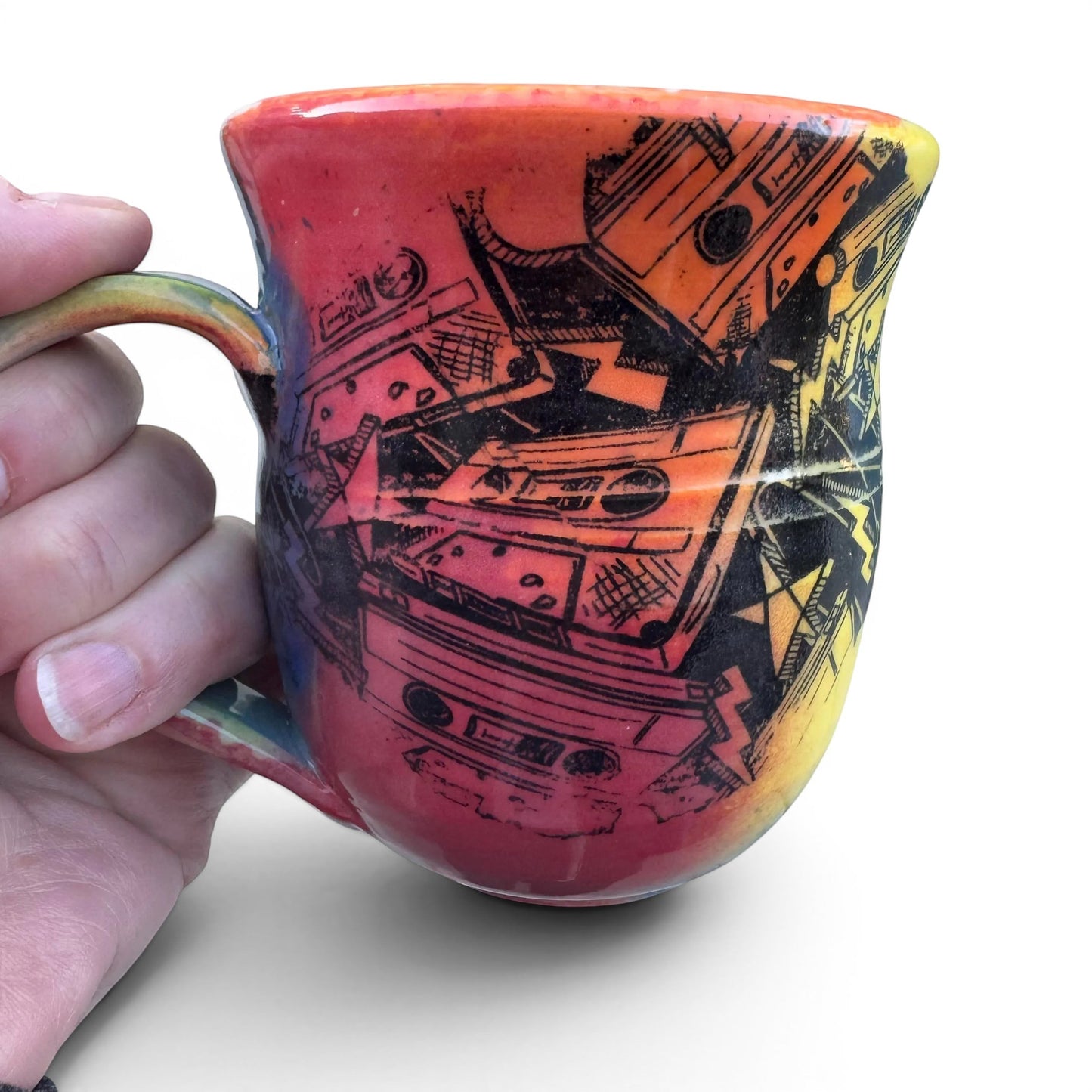 Rock N Art Shop handmade 12 oz ceramic mug with a bold, abstract cassette tape design in red, orange, and yellow.