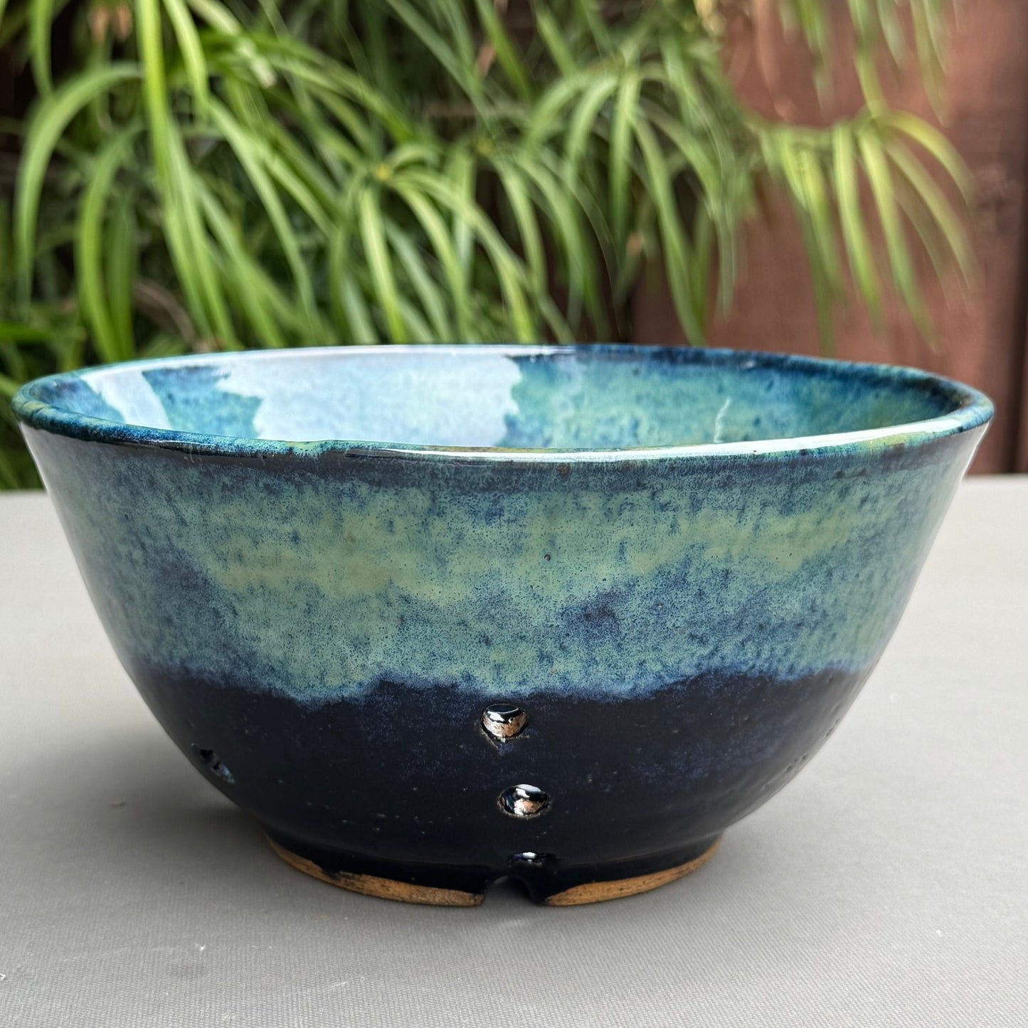 Rock N Art Shop handmade stoneware berry bowl with a blue and turquoise glaze and drainage holes for rinsing fruit.