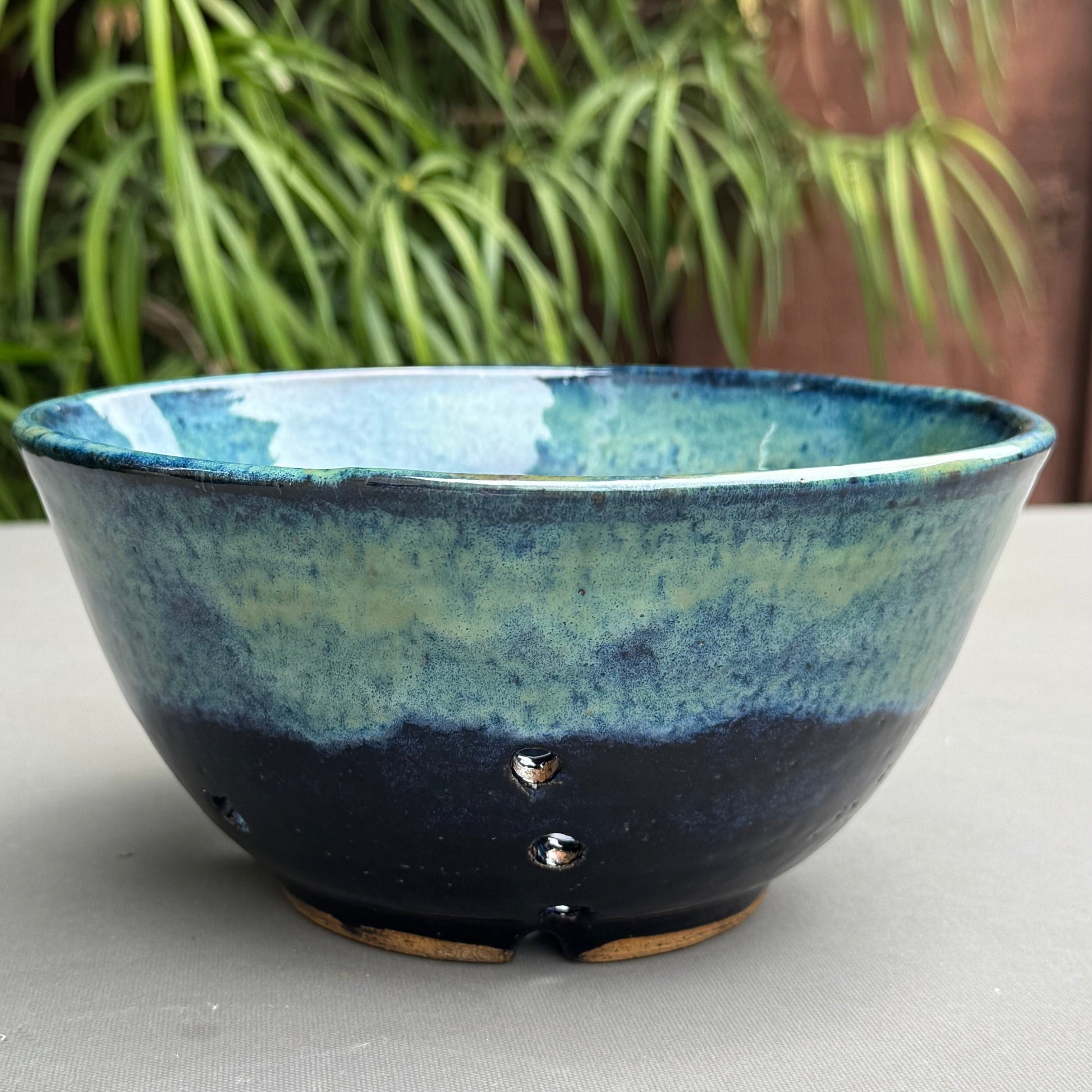 Rock N Art Shop handmade stoneware berry bowl with a blue and turquoise glaze and drainage holes for rinsing fruit.