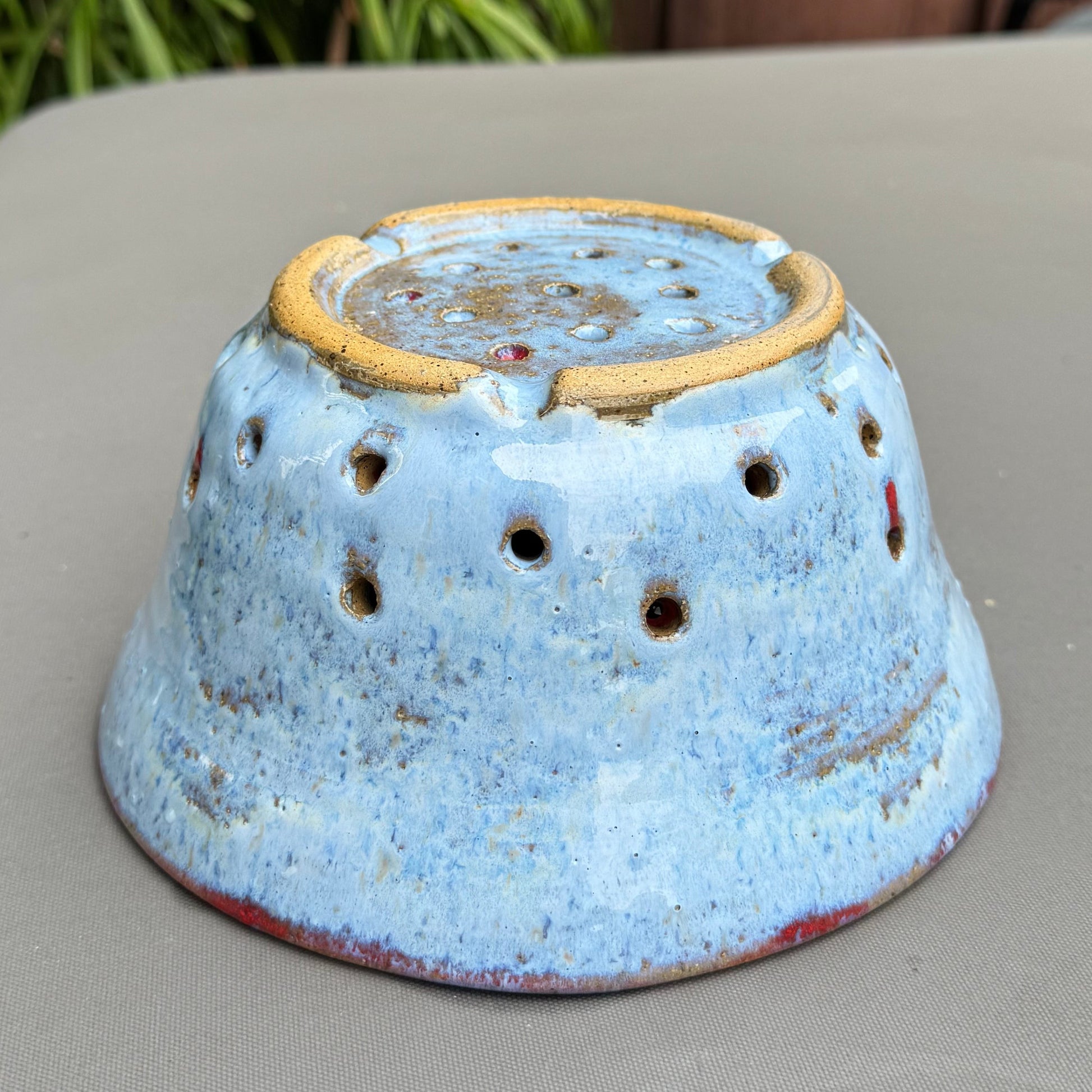 Rock N Art Shop handmade speckled buff stoneware berry bowl in cloud blue with drainage holes, inverted view.