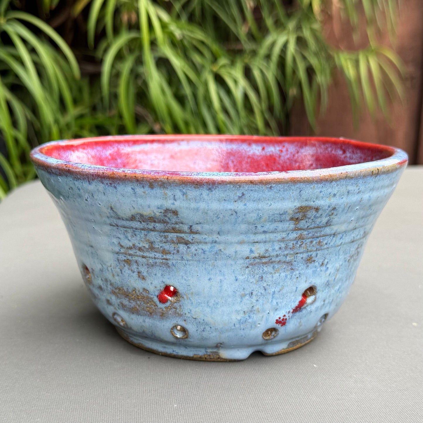 Rock N Art Shop handmade ceramic berry bowl with a speckled blue exterior and vibrant ruby red interior glaze.