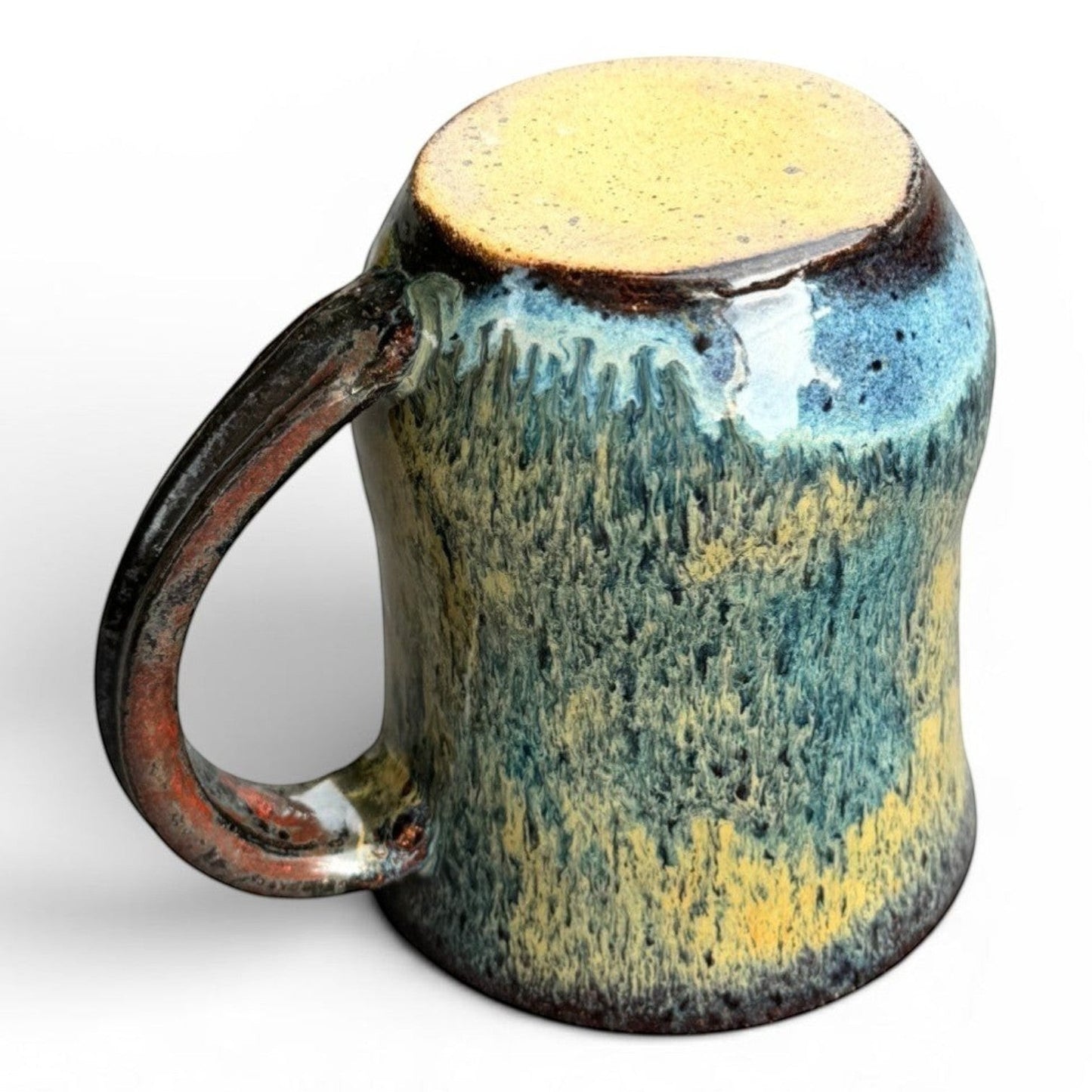 Rock N Art Shop handmade stoneware mug with blue, gold, and green drip glaze. Rustic wheel-thrown pottery with comfortable handle.