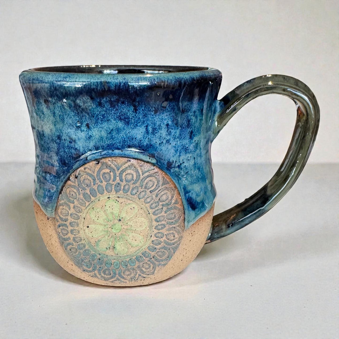 Rock N Art Shop handmade stoneware mug with ocean blue and seafoam green glaze, featuring a mandala relief appliqué.
