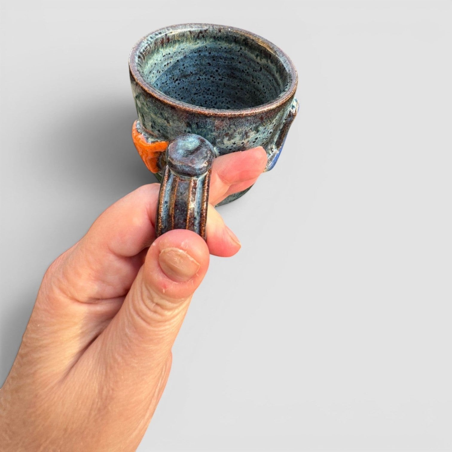 Rock N Art Shop handmade stoneware mug with speckled blue-green glaze and raised state design. Holds 12 oz.