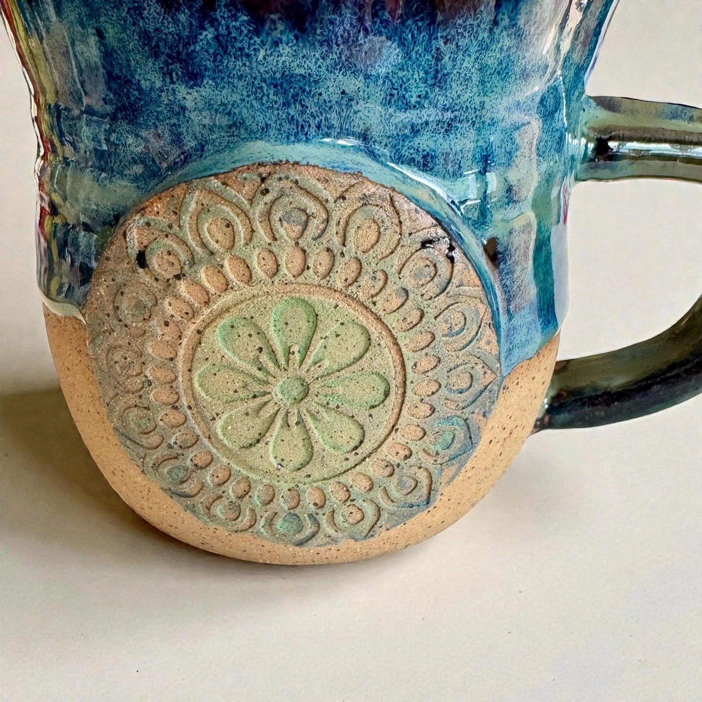 Rock N Art Shop handmade stoneware mug with ocean blue and seafoam green glaze, featuring a mandala medallion appliqué. 15 oz.