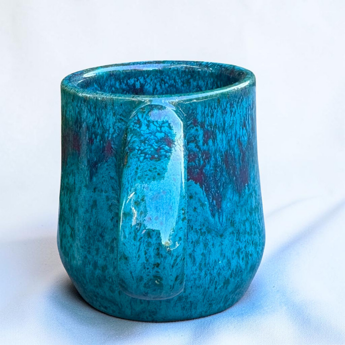 Rock N Art Shop handmade speckled stoneware coffee mug in glossy turquoise blue and purple glaze.