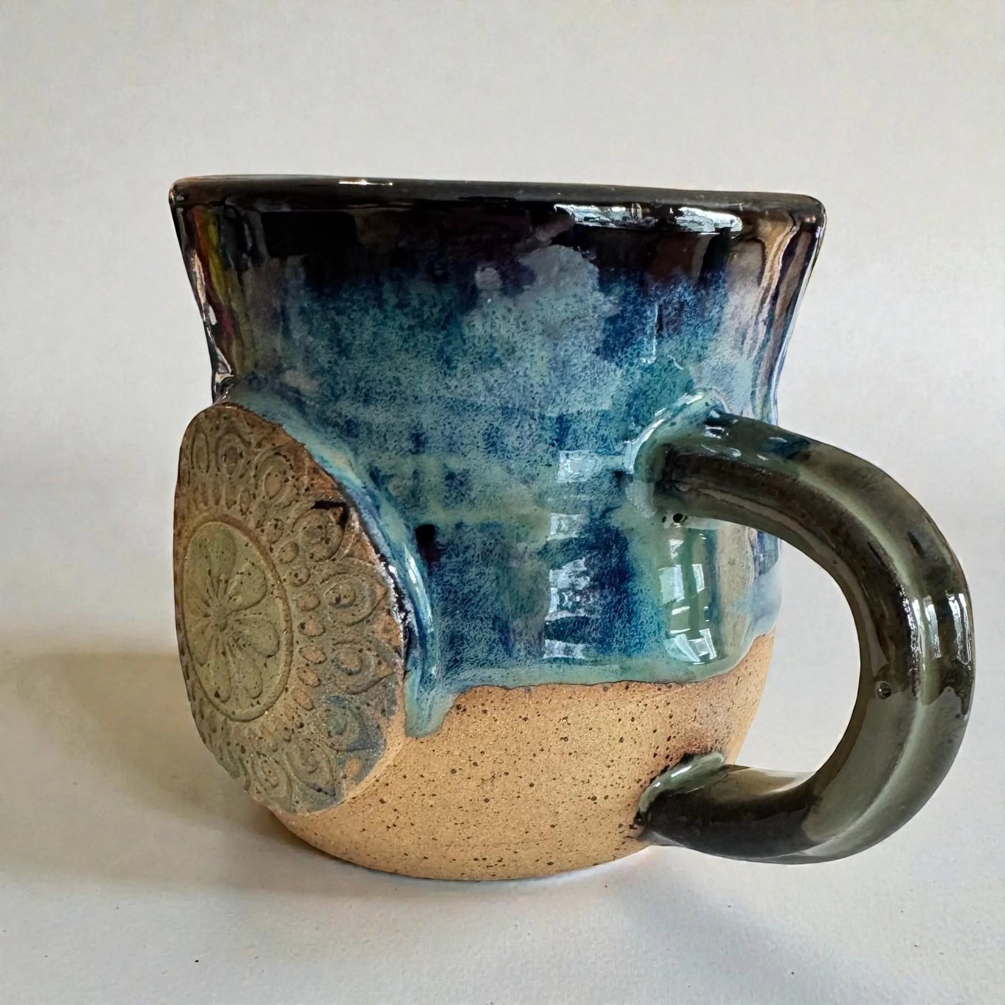 Rock N Art Shop handmade 15 oz stoneware mug with ocean blue and seafoam green glaze, featuring a mandala medallion appliqué.