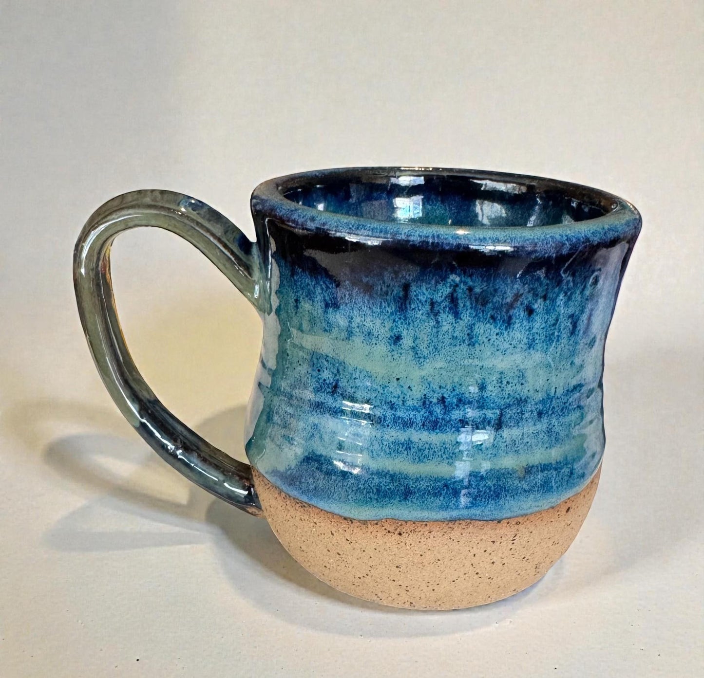 Rock N Art Shop handmade stoneware mug with ocean blue and seafoam green glaze, mandala relief, and speckled buff clay base.