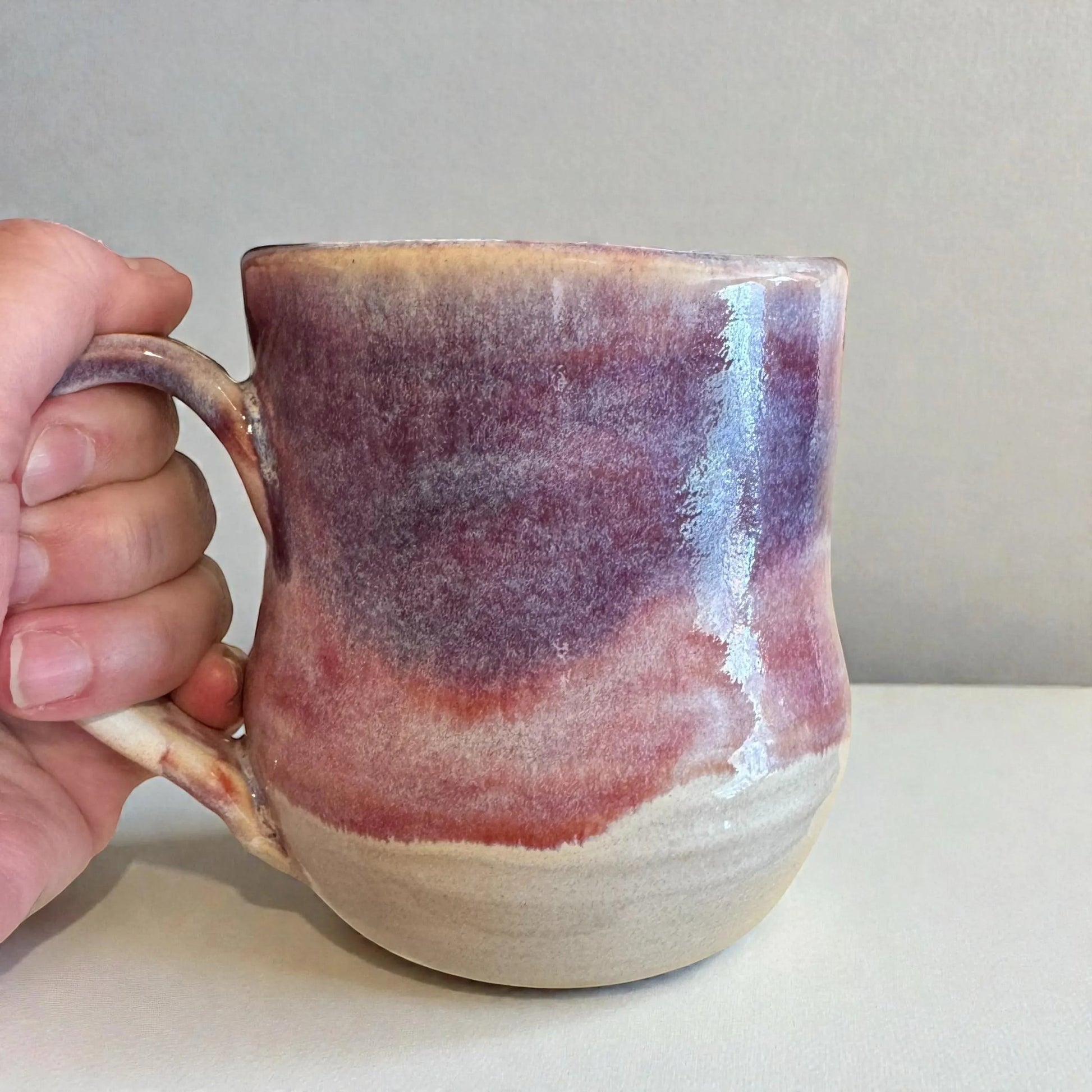Rock N Art Shop handmade 12 oz stoneware mug with plum and mauve glaze, featuring a comfortable handle and unique layered color finish.