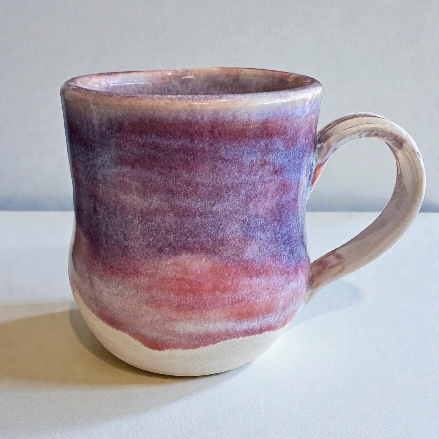 Rock N Art Shop 12 oz handmade stoneware mug with layered plum, mauve, and neutral glaze. Features a comfortable handle and satin-to-gloss finish.