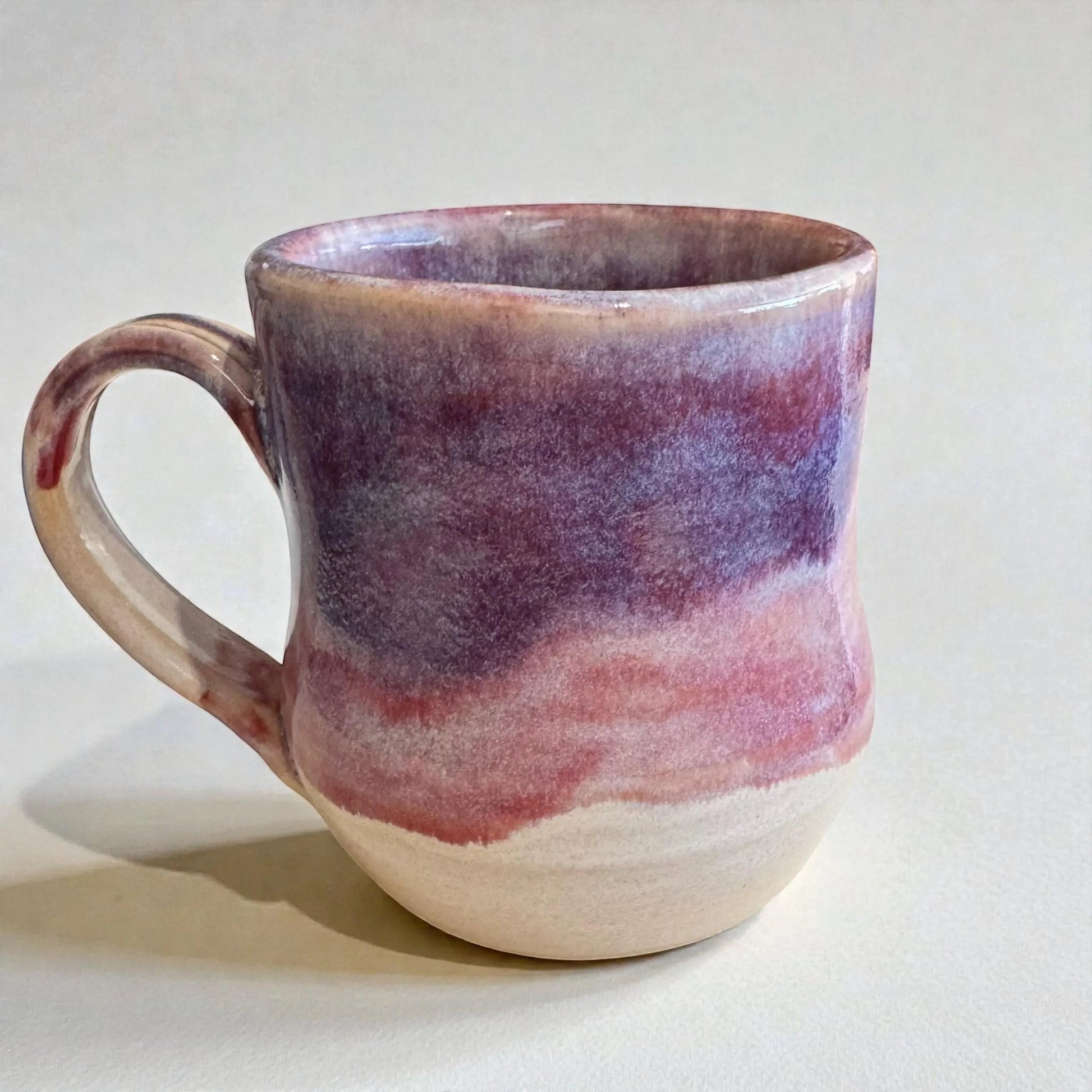 Rock N Art Shop handmade 12 oz stoneware mug with plum and mauve glaze. Wheel-thrown ceramic coffee mug with layered earthy tones.