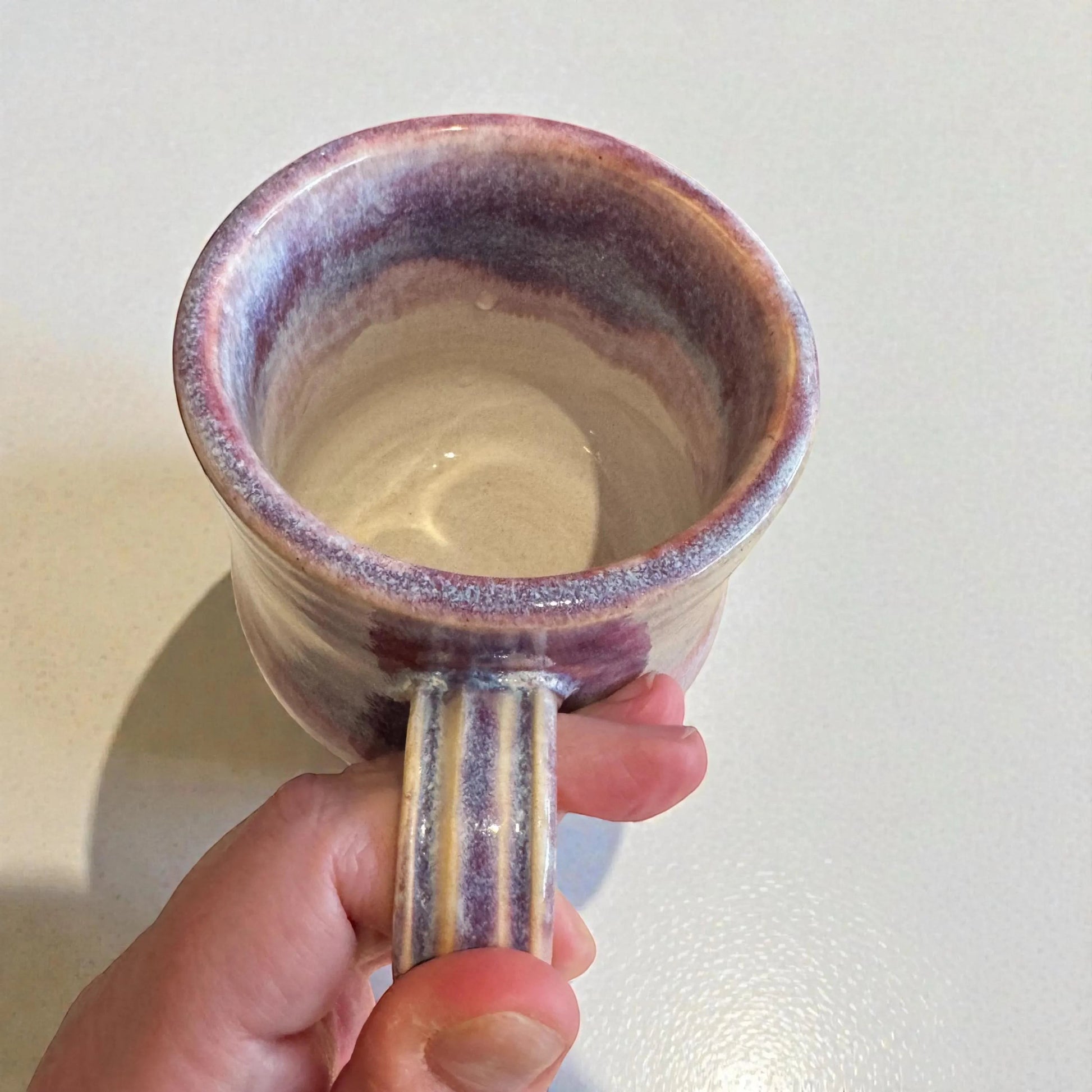 Rock N Art Shop handmade 12 oz stoneware mug with plum and mauve glaze. Features a ribbed handle and a satin-to-gloss finish.