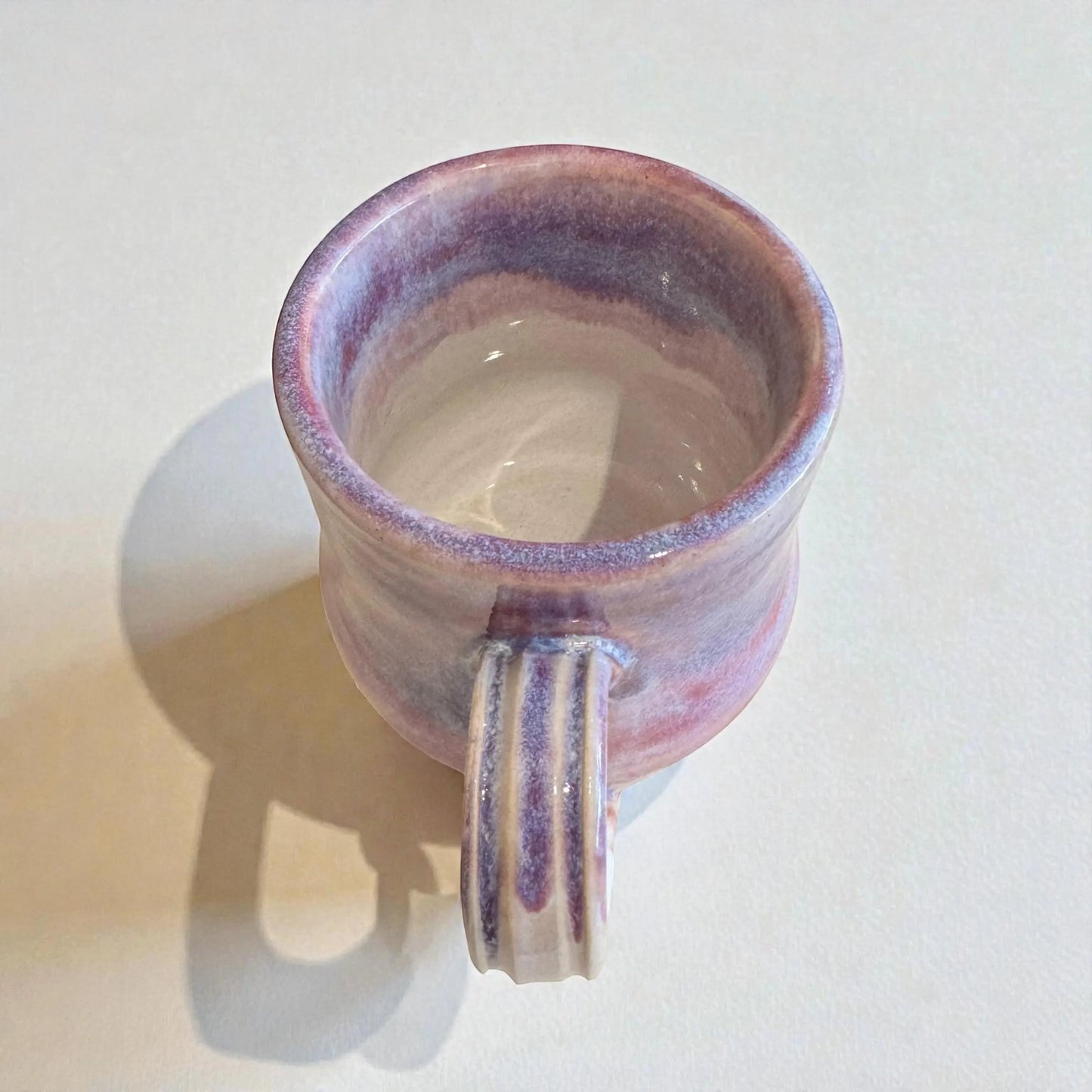 Rock N Art Shop handmade 12 oz stoneware mug with plum and mauve glaze. Features a ribbed handle and a satin-to-gloss finish.