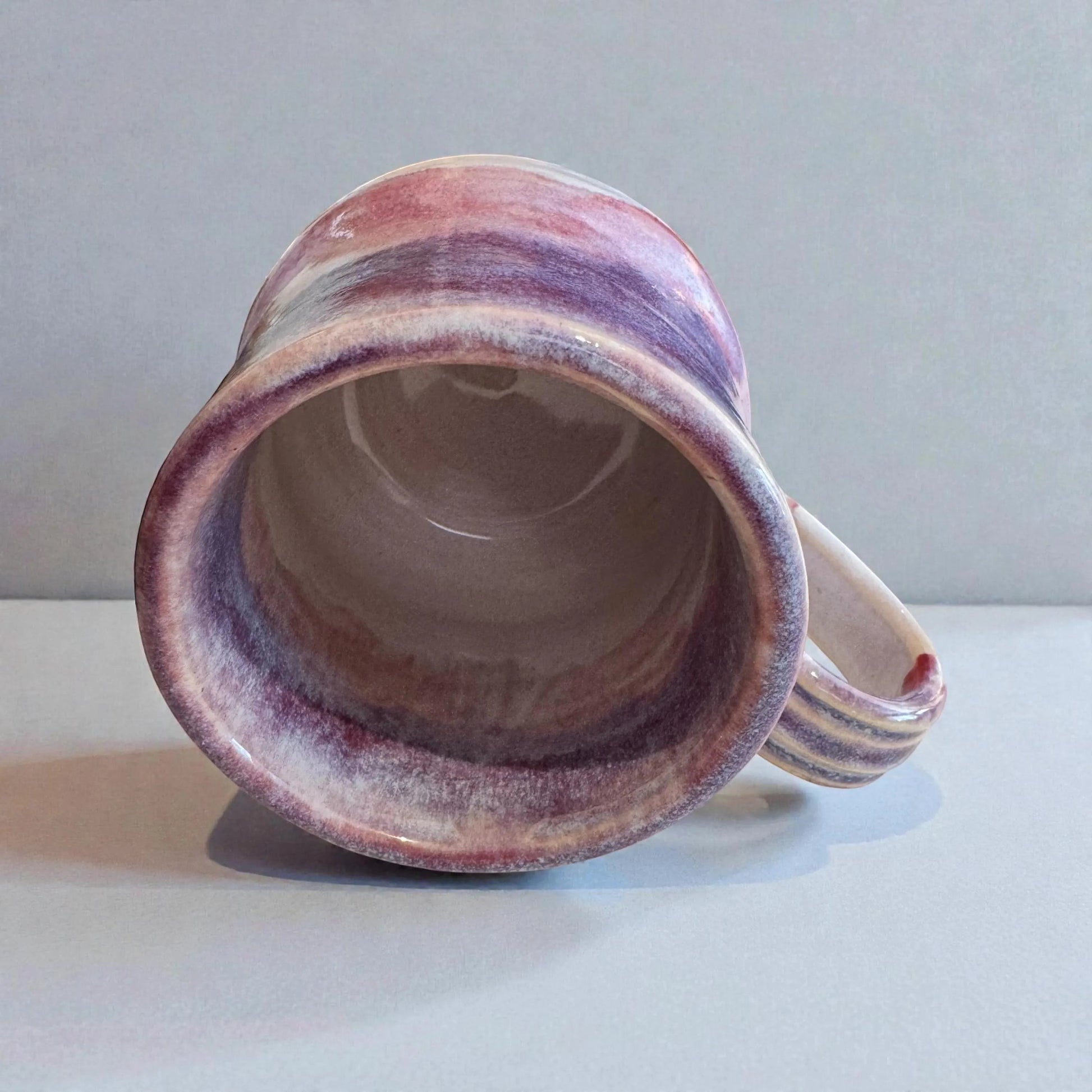 Rock N Art Shop handmade 12 oz stoneware mug with layered plum, mauve, and neutral glazes. Wheel-thrown ceramic coffee mug.