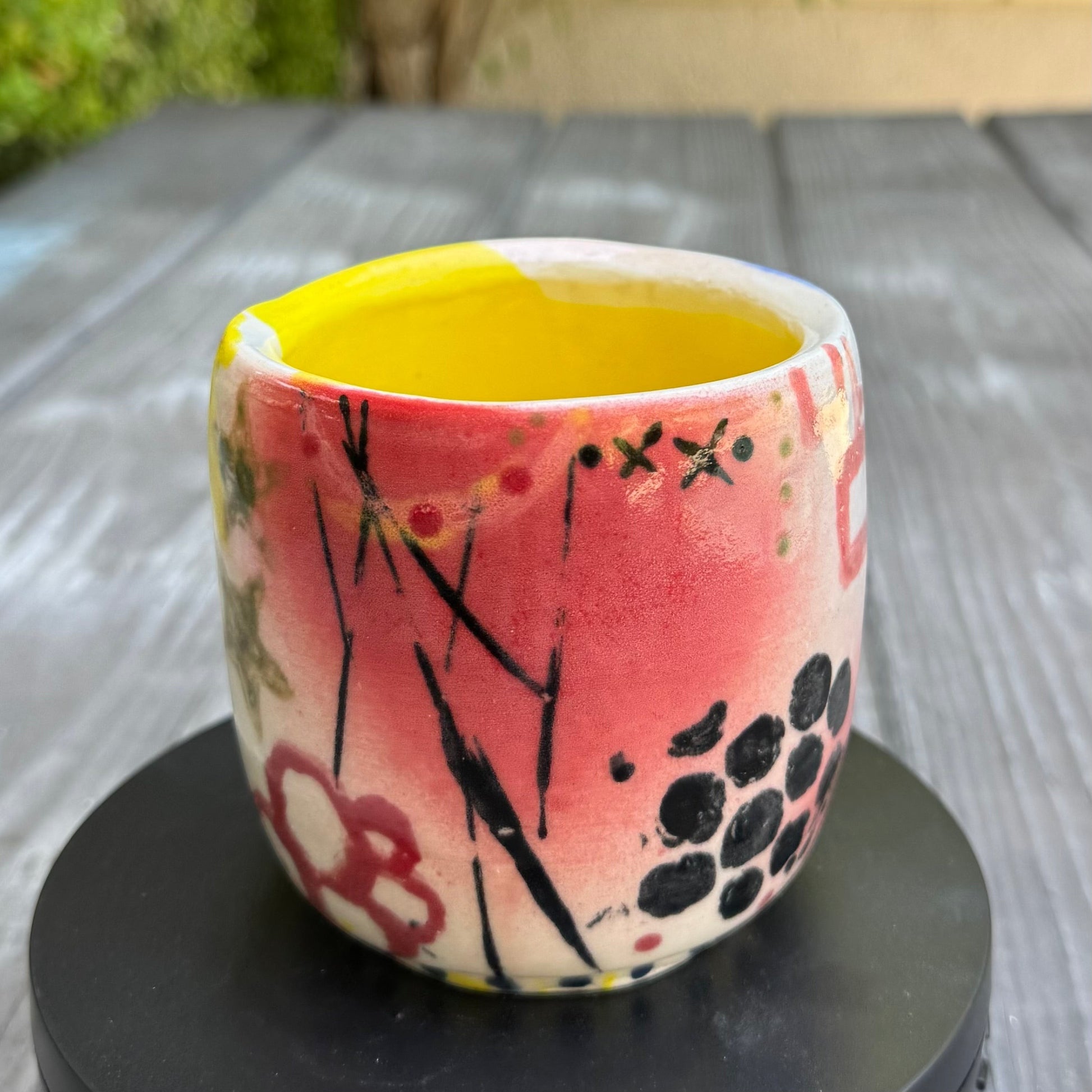 Rock N Art Shop hand-painted stoneware tumbler, 12 oz, with abstract pop art design in pink, blue, yellow, and black. Bright yellow interior.