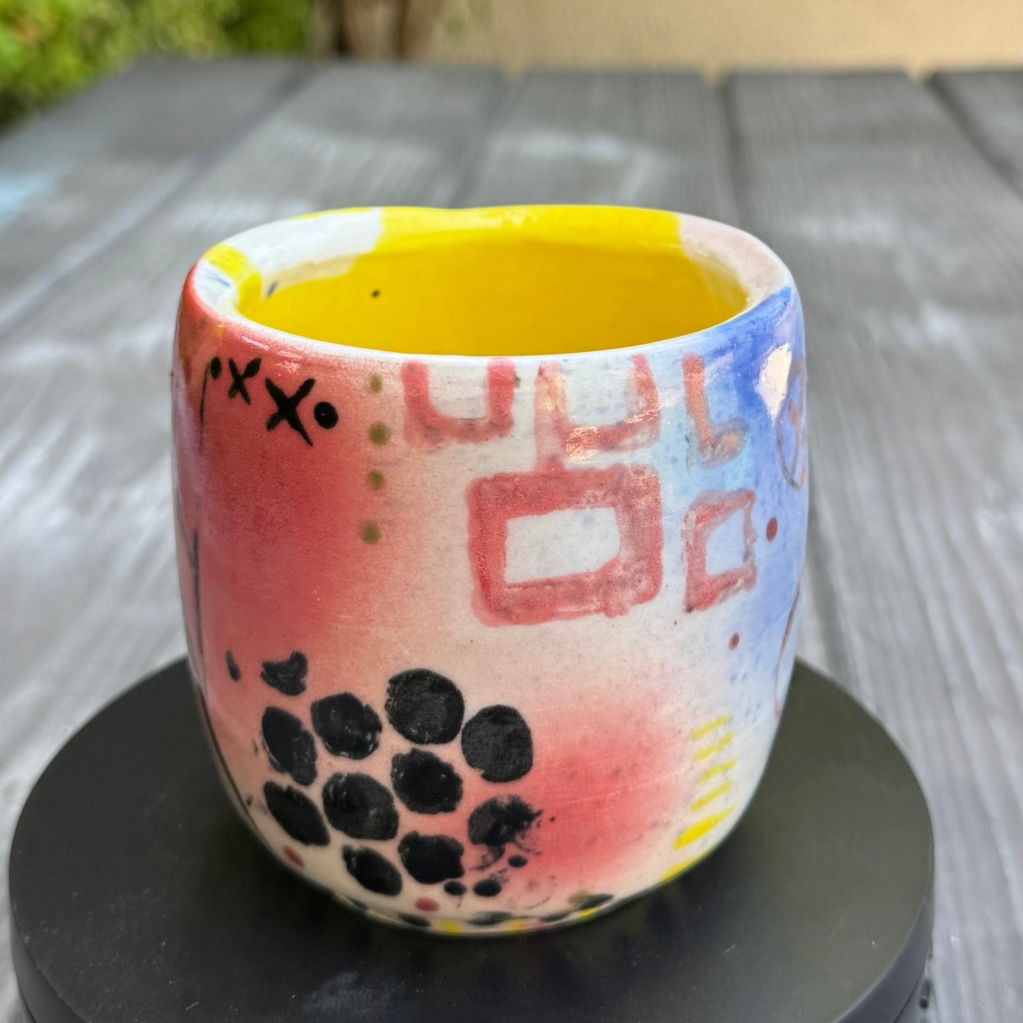 Rock N Art Shop hand-painted stoneware tumbler, 12 oz, with abstract pop art design in pink, blue, yellow, and black. Bright yellow interior.