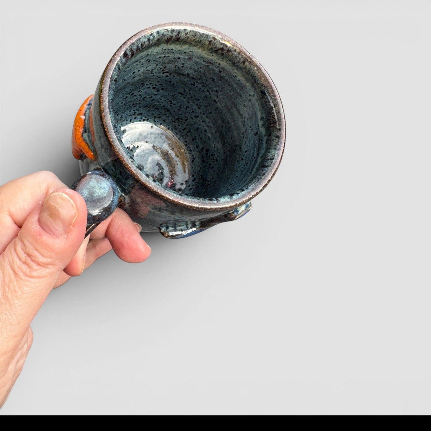 Rock N Art Shop handmade speckled blue-green stoneware coffee mug with raised state design and orange accents.