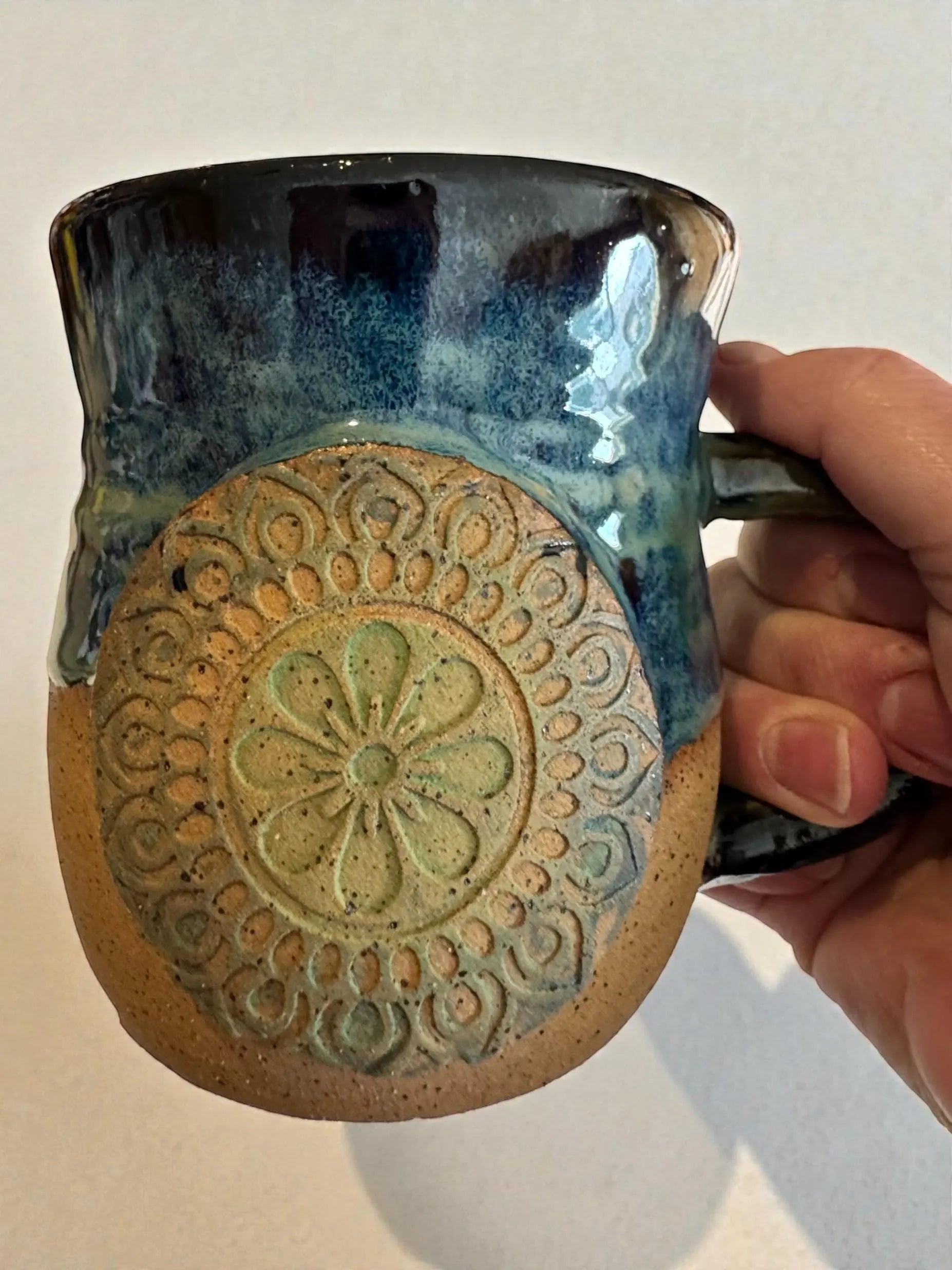 Rock N Art Shop handmade 15 oz stoneware mug with ocean blue and seafoam green glaze, featuring a textured mandala medallion appliqué.