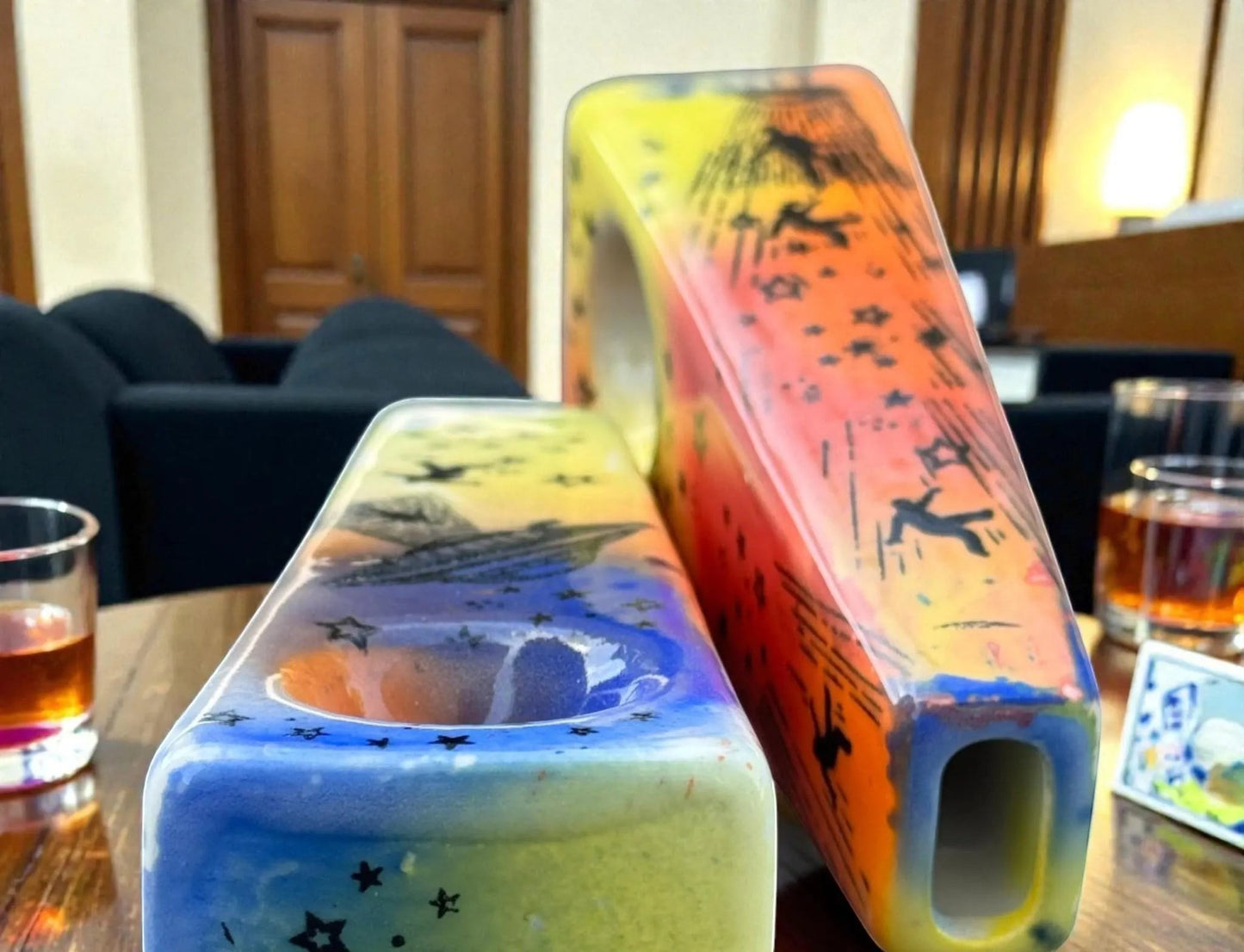 Rock N Art Shop hand-decorated ceramic pipe with UFO and cosmic star design, vibrant blue, yellow, and orange glaze.